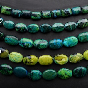 May include: Six strands of oval-shaped green and blue gemstone beads. The beads are arranged in rows, with the top row being the smallest and the bottom row being the largest. The beads are all different shades of green and blue, with some having a more yellow hue.