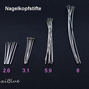 Może przedstawiać: Różne srebrne szpilki z główką o różnych długościach, na ciemnym tle. Obraz zawiera wymiary 2,6, 3,1, 5,9 i 8, wskazujące długości szpilek w mm. Tekst "Nagelkopfstifte" znajduje się u góry, a "MaxiBlue" u dołu.