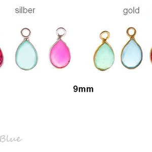 Peut inclure: Six breloques en verre en forme de goutte d'eau dans des montures argentées et dorées. Les breloques mesurent 9 mm et sont disponibles en rose, vert et bleu. Les breloques sont étiquetées "silber" et "gold".