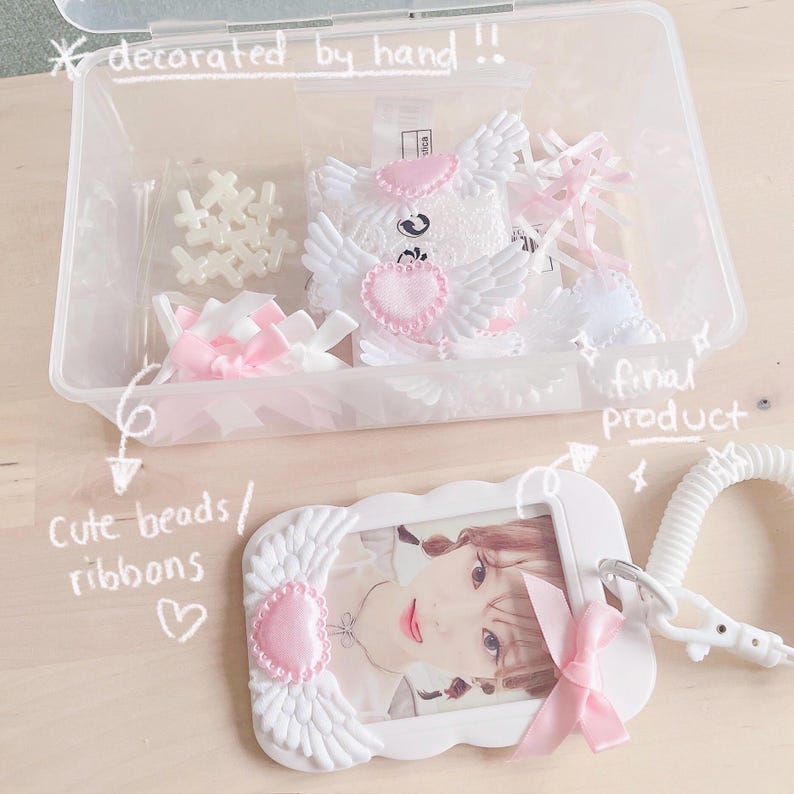 May include: A white plastic frame with pink and white wings and a pink heart. The frame has a photo of a person inside. The frame is attached to a white plastic lanyard with a white plastic clip. The frame is decorated with pink and white ribbons. The text "final product" is written on the image.