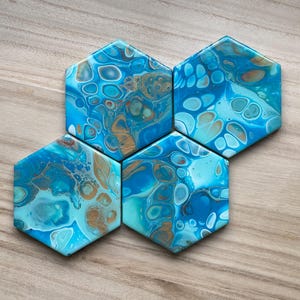 May include: Set of six hexagonal coasters with a blue, white, and gold abstract swirl pattern.