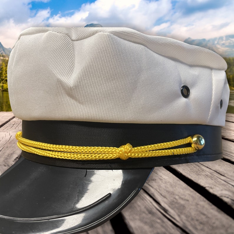 May include: A white captain's hat with a black band and a gold rope trim. The hat has a black visor and a gold button on the side.