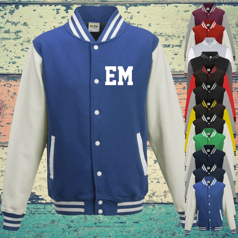 May include: A royal blue varsity jacket with cream-coloured sleeves, a striped ribbed collar, cuffs, and hem. The front features white snap buttons, two side pockets, and the white letters EM printed on the left chest. A column of various coloured jackets is visible.