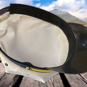 May include: White and black captain's hat with a gold trim. The hat is turned inside out, showing the black lining.