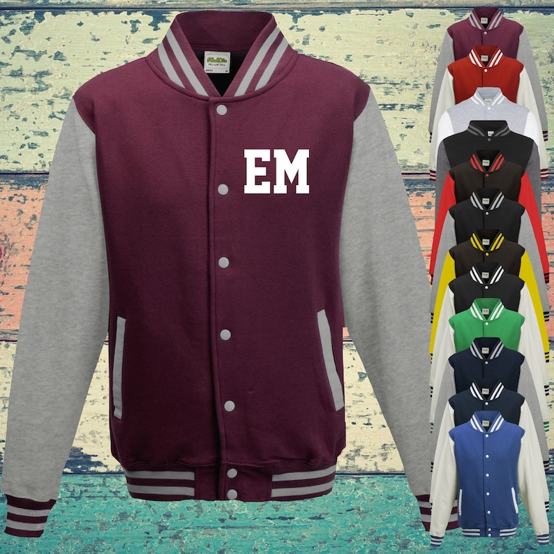 May include: A burgundy varsity jacket with grey sleeves, a striped collar, cuffs, and hem, featuring the white letters EM on the chest. The front includes a button-down closure and two side pockets. A vertical display of various colour options is shown.