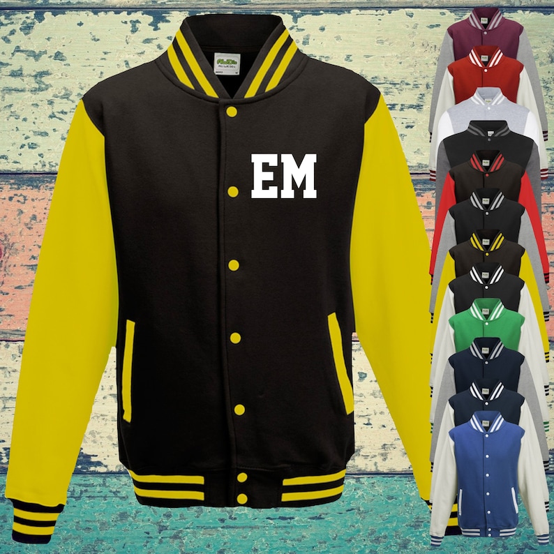 May include: A black varsity jacket with yellow sleeves, yellow striped ribbed cuffs, collar, and hem. The jacket features a front snap button closure, two side pockets, and the white letters EM printed on the left chest. A column of various coloured jackets is visible on the right side.