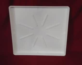 May include: White plastic tray with a raised starburst design in the center. The tray is rectangular and has a smooth surface.