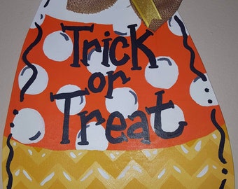 May include: A wooden candy corn door hanger with a burlap bow and the words "Trick or Treat" painted in black.