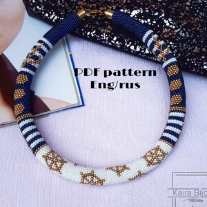 Könnte beinhalten: Eine blaue, weiße und goldene Perlenkette mit nautischem Thema. Die Kette ist aus Perlen gefertigt und zeigt ein Muster aus Ankern und Streifen. Das Bild enthält den Text "PDF pattern Eng/rus".
