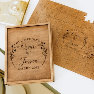 May include: A wooden box with a personalized inscription for a wedding. The inscription reads "OUR WEDDING Oscar & Jessica Oct 21th, 2025". The box is open and a wooden jigsaw puzzle is visible inside. The puzzle is also personalized with the couple's names and wedding date.