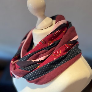 Könnte beinhalten: Ein unendlich langer Schal in Burgunderrot, Rosa und Marineblau mit geometrischem Muster. Der Schal ist aus weichem, dehnbarem Stoff gefertigt und perfekt, um jedem Outfit einen Farbtupfer zu verleihen.