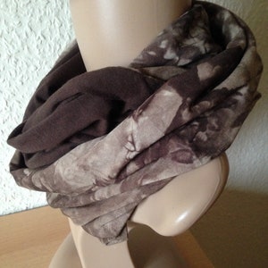 Puede incluir: Una bufanda infinita de patrón marrón y beige. La bufanda está hecha de un tejido suave y elástico, perfecta para mantenerse caliente en invierno.