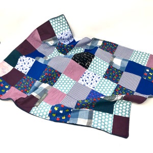May include: A patchwork quilt made from various blue, green, and purple fabrics with different patterns, including polka dots, plaid, and floral prints.