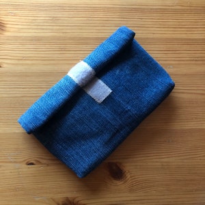 May include: A small blue denim pouch with a white fabric flap closure.