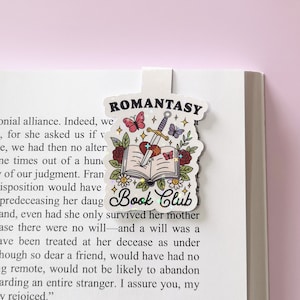 May include: A white bookmark featuring a colourful illustration of a book, sword, and butterflies. The text "ROMANTASY Book Club" is printed on the bookmark.