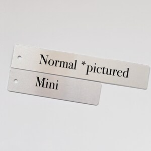 May include: Two silver metal tags with black text. The top tag reads "Normal * pictured". The bottom tag reads "Mini".