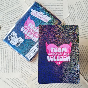 May include: A holographic sticker with a pink heart and devil horns that says "Team whoever the villain is".