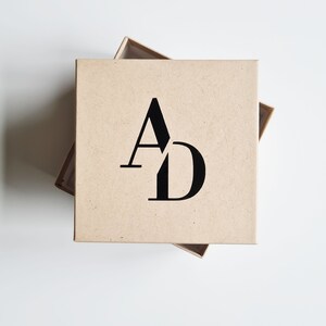 May include: A brown cardboard box with the letters "AD" printed in black on the top.