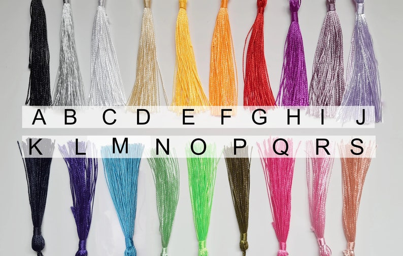 May include: A chart of 19 different colored tassels, labeled with letters A through S. The tassels are arranged in two rows, with the first row labeled A through J and the second row labeled K through S.