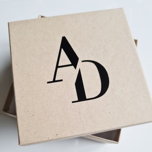 May include: A brown cardboard box with the letters "AD" printed in black on the top.