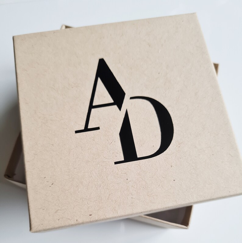 May include: A brown cardboard box with the letters "AD" printed in black on the top.