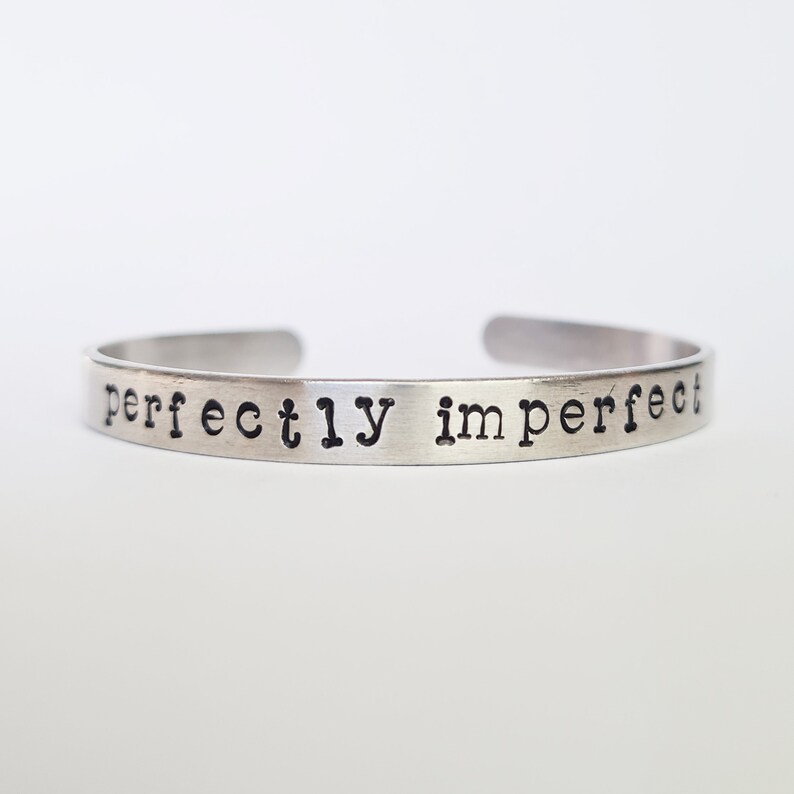 May include: Silver bracelet with the words "perfectly imperfect" engraved on it.