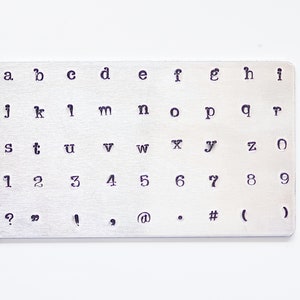 May include: A metal stamp set with uppercase letters, lowercase letters, numbers, and punctuation marks. The set includes the letters a through z, the numbers 1 through 9, and the punctuation marks ?, ", !, ', @, ., #, (, and ).