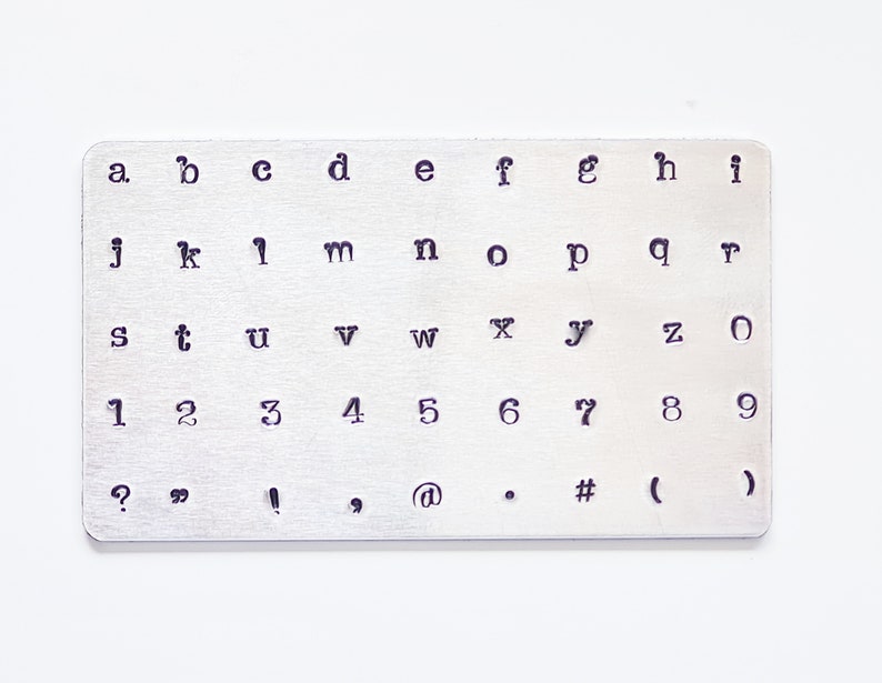 May include: A metal stamp set with uppercase letters, lowercase letters, numbers, and punctuation marks. The set includes the letters a through z, the numbers 1 through 9, and the punctuation marks ?, ", !, ', @, ., #, (, and ).