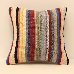 May include: A colorful striped throw pillow with a white background. The pillow is made of woven fabric and has a variety of colors, including red, blue, green, yellow, and pink.
