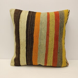 May include: A striped throw pillow with a brown, orange, yellow, and white color scheme. The pillow is made of a woven fabric and has a square shape.