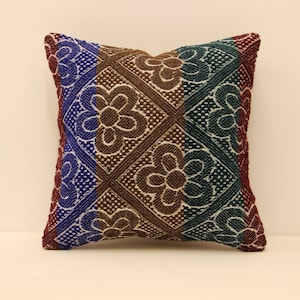 May include: A square pillow with a brown, blue, and green striped pattern. The pattern features a repeating floral design.