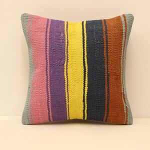 May include: A square throw pillow with a striped pattern in shades of pink, purple, yellow, blue, and brown.