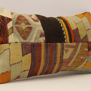 May include: A rectangular cushion with a patchwork design. The cushion is made of different fabrics with various colours and patterns, including red, orange, yellow, brown, and green. The cushion is made of a woven fabric with a textured surface.