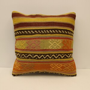 May include: A colorful striped throw pillow with a geometric pattern. The pillow is made of woven fabric in shades of yellow, brown, orange, red, and green.