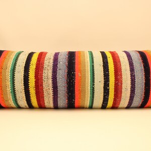 May include: A long, rectangular pillow with a colorful striped pattern. The stripes are in various shades of red, orange, yellow, green, blue, purple, and black.