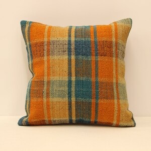 May include: Orange, blue, and beige plaid throw pillow. The pillow is made of woven fabric and has a square shape.