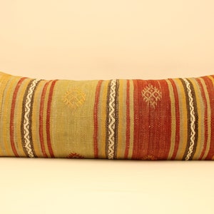May include: A long, rectangular pillow with a colorful striped pattern. The pillow is made of woven fabric with a variety of colors, including red, yellow, green, and brown. The pillow has a traditional, ethnic design.