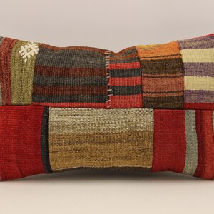 May include: A rectangular patchwork cushion with a variety of colours and patterns, including red, orange, brown, and white. The cushion is made of woven fabric and has a slightly textured surface.
