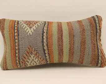 May include: A long, rectangular pillow with a woven pattern in shades of brown, orange, and gray. The pillow has a striped design with geometric patterns.