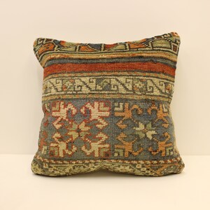 May include: A square pillow with a colorful geometric pattern in shades of blue, green, orange, and red. The pillow is made of a woven fabric with a textured surface.