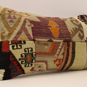 May include: A rectangular cushion with a patchwork design. The cushion is made of different fabrics with various colours and patterns, including red, orange, purple, and black. The cushion is made of a woven fabric with a textured surface.