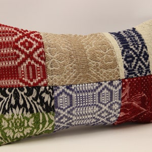 Puede incluir: Una almohada rectangular de patchwork con una variedad de colores y patrones, incluyendo rojo, azul, verde, negro y blanco.