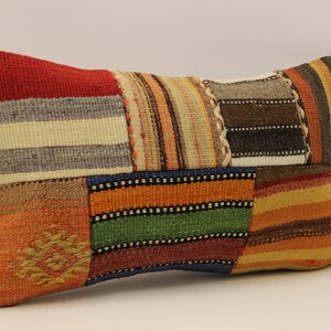 May include: A rectangular pillow with a patchwork design featuring various colors and patterns, including red, orange, yellow, green, blue, brown, and white.