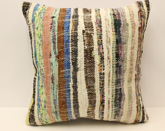 May include: Square pillow with a woven, striped design. The pillow features vertical stripes in various colors, including white, brown, blue, pink, and green. The pillow's edges are finished with a black border.