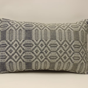 May include: A rectangular throw pillow with a geometric pattern in shades of gray and white.
