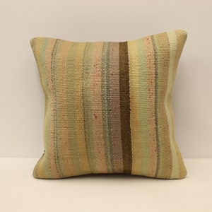 May include: A square throw pillow with a striped pattern in shades of beige, brown, pink, and green. The pillow is made of woven fabric and has a soft, textured surface.