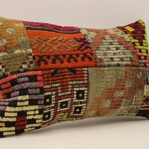 May include: A rectangular patchwork pillow with a variety of colors and patterns, including red, orange, brown, black, and white. The pillow is made of woven fabric and has a slightly textured surface.