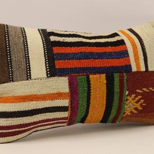 May include: A rectangular patchwork cushion with a variety of colourful stripes in shades of brown, white, orange, red, green, blue, and black.