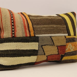 Può includere: Un cuscino rettangolare in patchwork con una varietà di colori e motivi, tra cui marrone, beige, giallo, arancione e rosso. Il cuscino è realizzato in tessuto tessuto e ha una superficie leggermente strutturata.