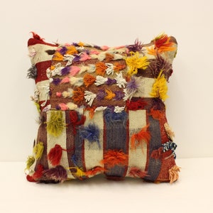 May include: A colorful, striped throw pillow with a patchwork design and fringe details. The pillow is made of woven fabric and has a variety of colors, including red, orange, yellow, green, blue, and purple.